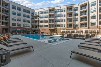An outdoor pool with chaise lounge chairs and a building in the background